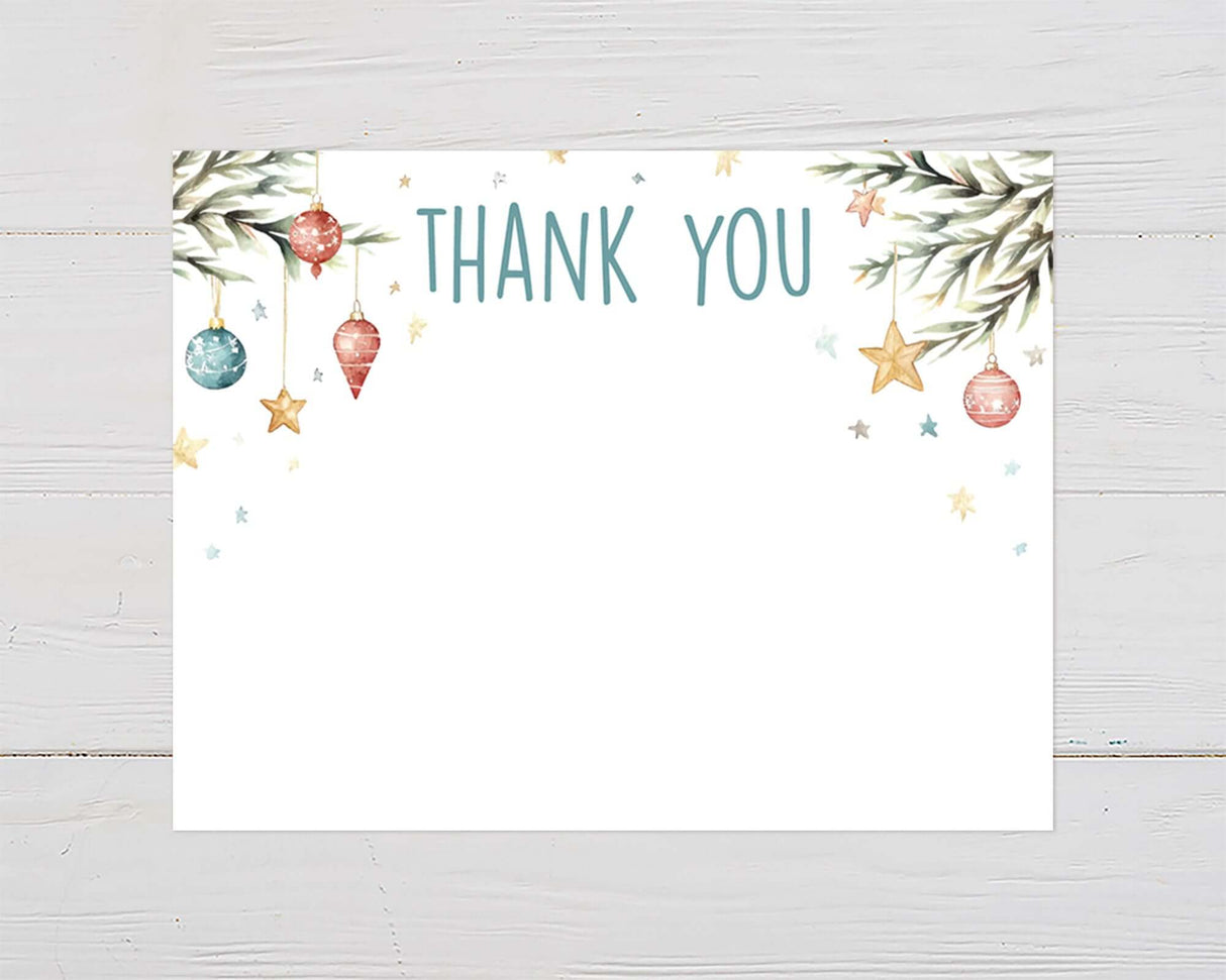 Christmas baby shower thank you card with watercolor ornaments, stars, and pine branches on white wood background