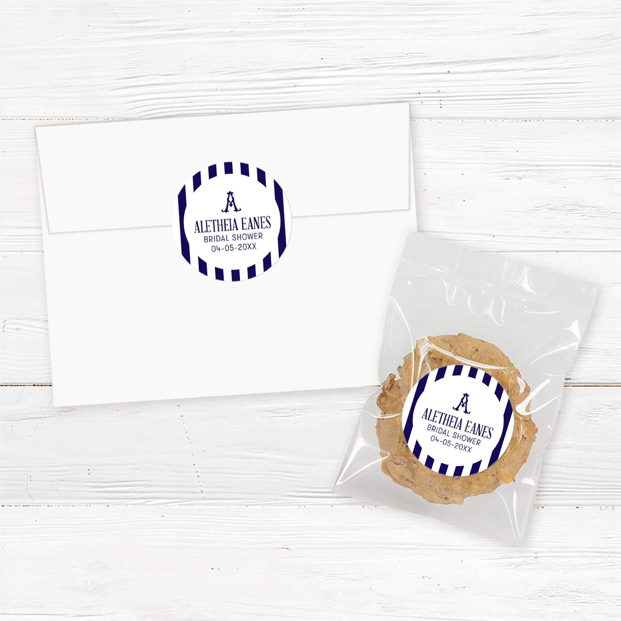 Bridal shower sticker with navy and white vertical stripes, antique-style serif monogram at the top, rounded arch shape, and modern script and serif font for favors or envelope seals.