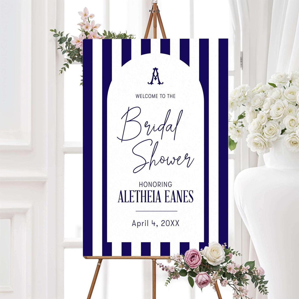 Bridal shower welcome sign with navy and white vertical stripes, antique serif monogram, elegant modern script and serif fonts, and a white arch panel to welcome guests in style.