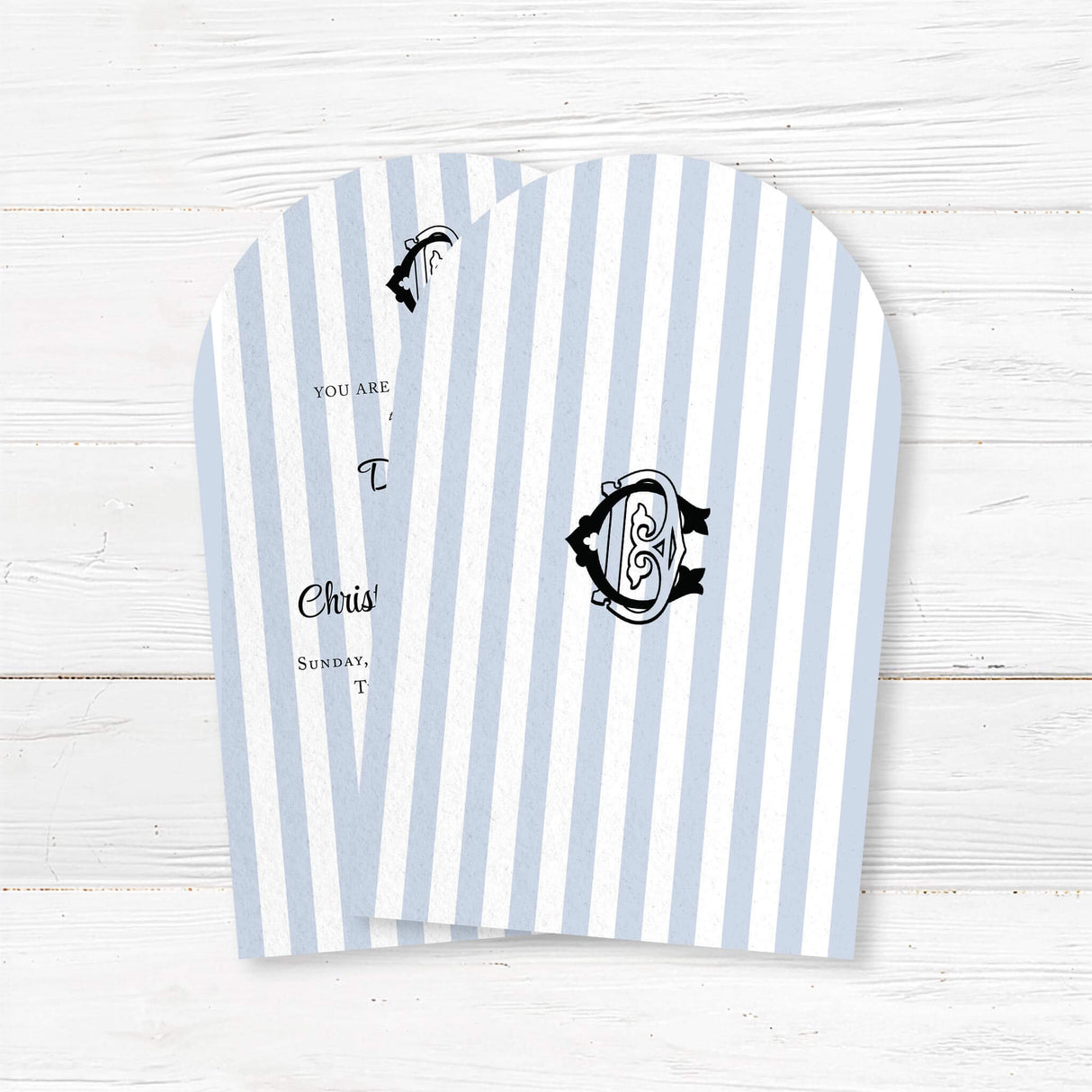 Arched wedding invitation with vertical light blue and white stripes, elegant black crest monogram at the top, and a mix of serif and script fonts for a classic and refined look, ideal for coastal or nautical wedding themes. - back side