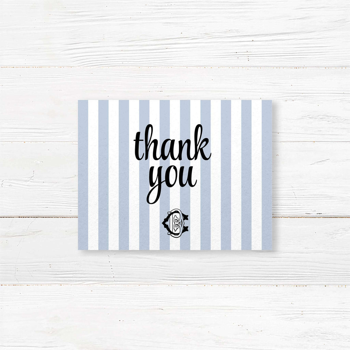 Wedding thank you card with light blue and white vertical stripes and elegant monogram crest, coordinated with matching wedding suite for a refined finish.