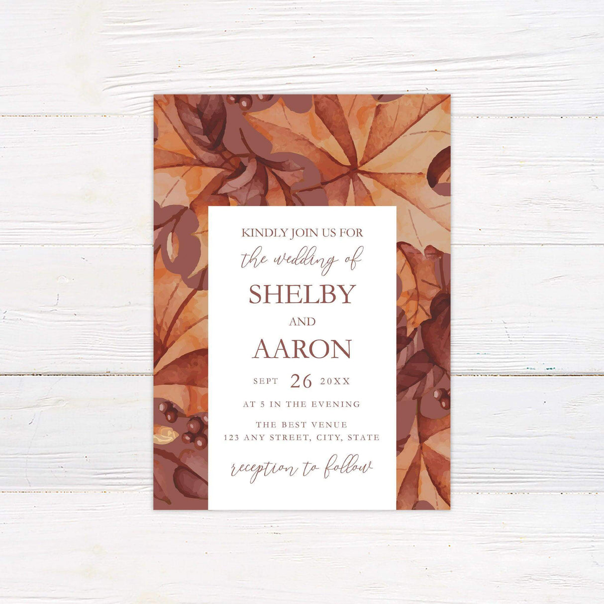 Wedding invitation with autumn foliage border in burgundy, burnt orange, and golden yellow, featuring elegant fall design elements.