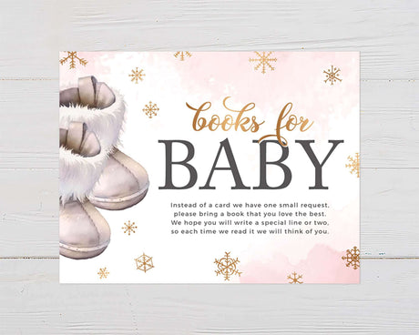 "Books for Baby" invitation with pink watercolor background and snowflakes, featuring cozy boots illustration for a winter baby shower.