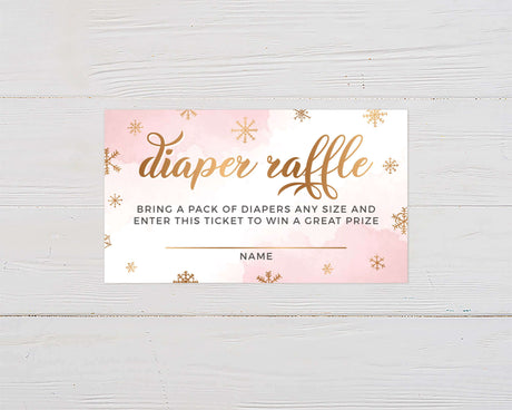 Pink diaper raffle ticket card design with gold snowflakes on white wood background for baby shower event.