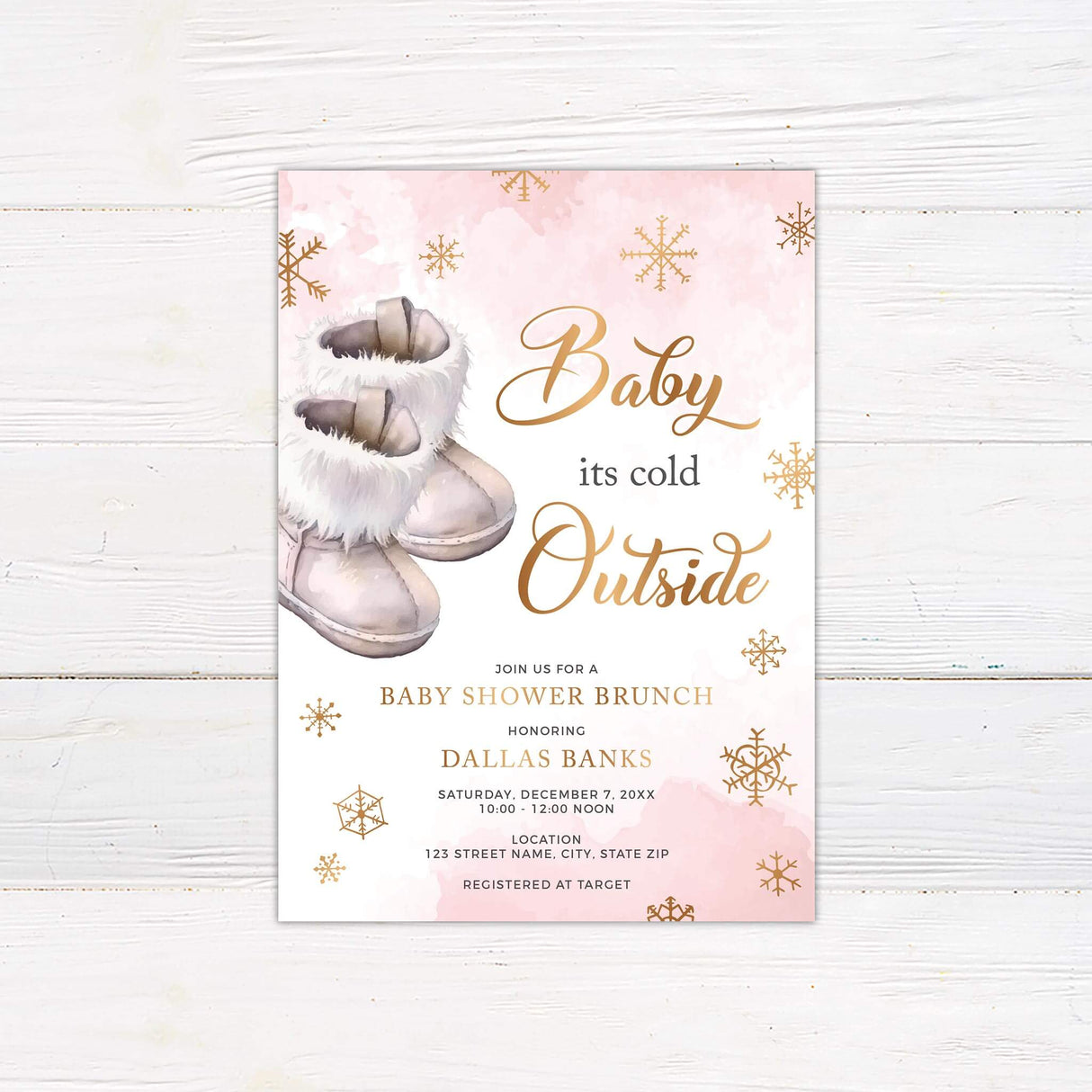 Baby It's Cold Outside pink baby shower invitation featuring snowflakes and baby boots on a rustic wooden background.