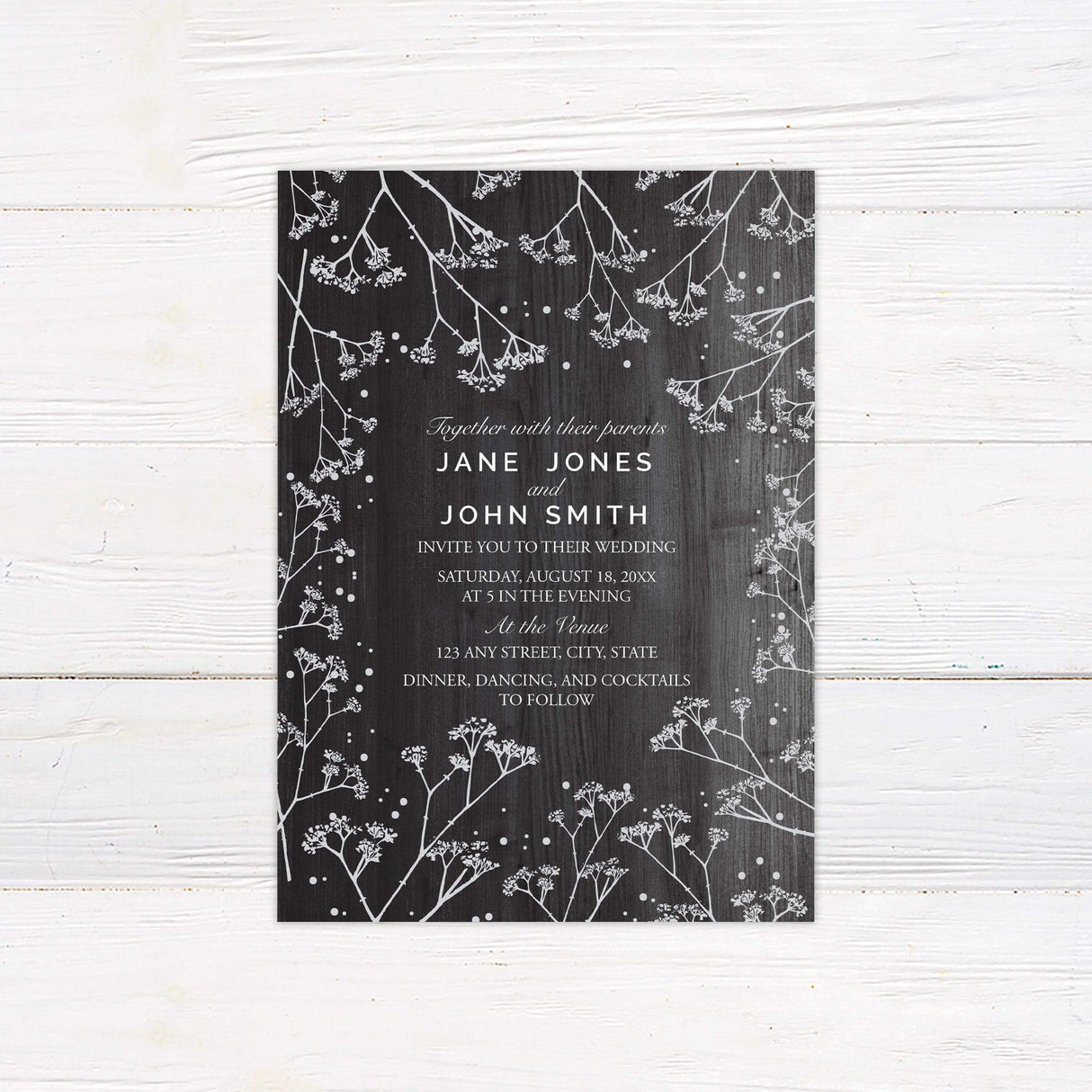 Rustic wedding invitation with dark wood background, white baby's breath floral accents, and elegant script and serif fonts for an outdoor or barn wedding.