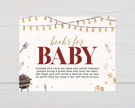 Baby shower invitation with "Books for Baby" theme, string lights, barbecue grill, and baby items on white wood background.