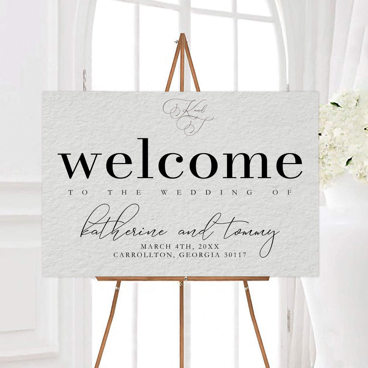 Elegant beautifully written script wedding welcome sign featuring oversized typography, flowing script, and a subtle textured background. The design includes a personalized monogram, couple’s names, wedding date, and location.