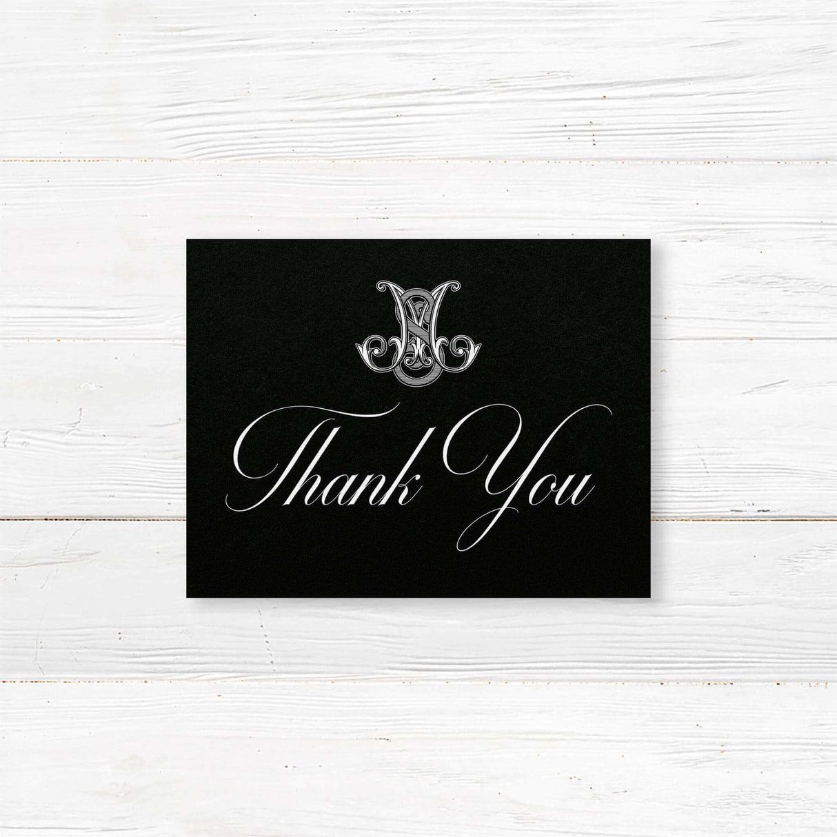Black Celtic Monogram Wedding Invitation - Black Celtic monogram thank you card with script fonts on white wood background.
