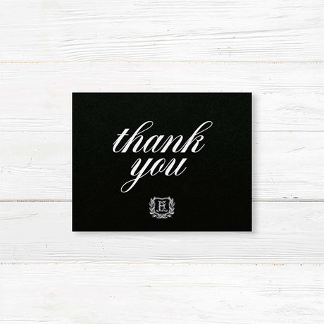 Black Wreath Shield Wedding Invitation - Wedding thank you card with black background, white calligraphy fonts, and an ornate shield monogram encircled by a laurel wreath, matching a formal black wedding suite.-