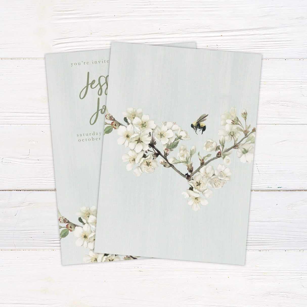 Spring wedding invitation with green background, white blossoms, a watercolor bumblebee, and elegant script—perfect for garden or nature-themed weddings. back