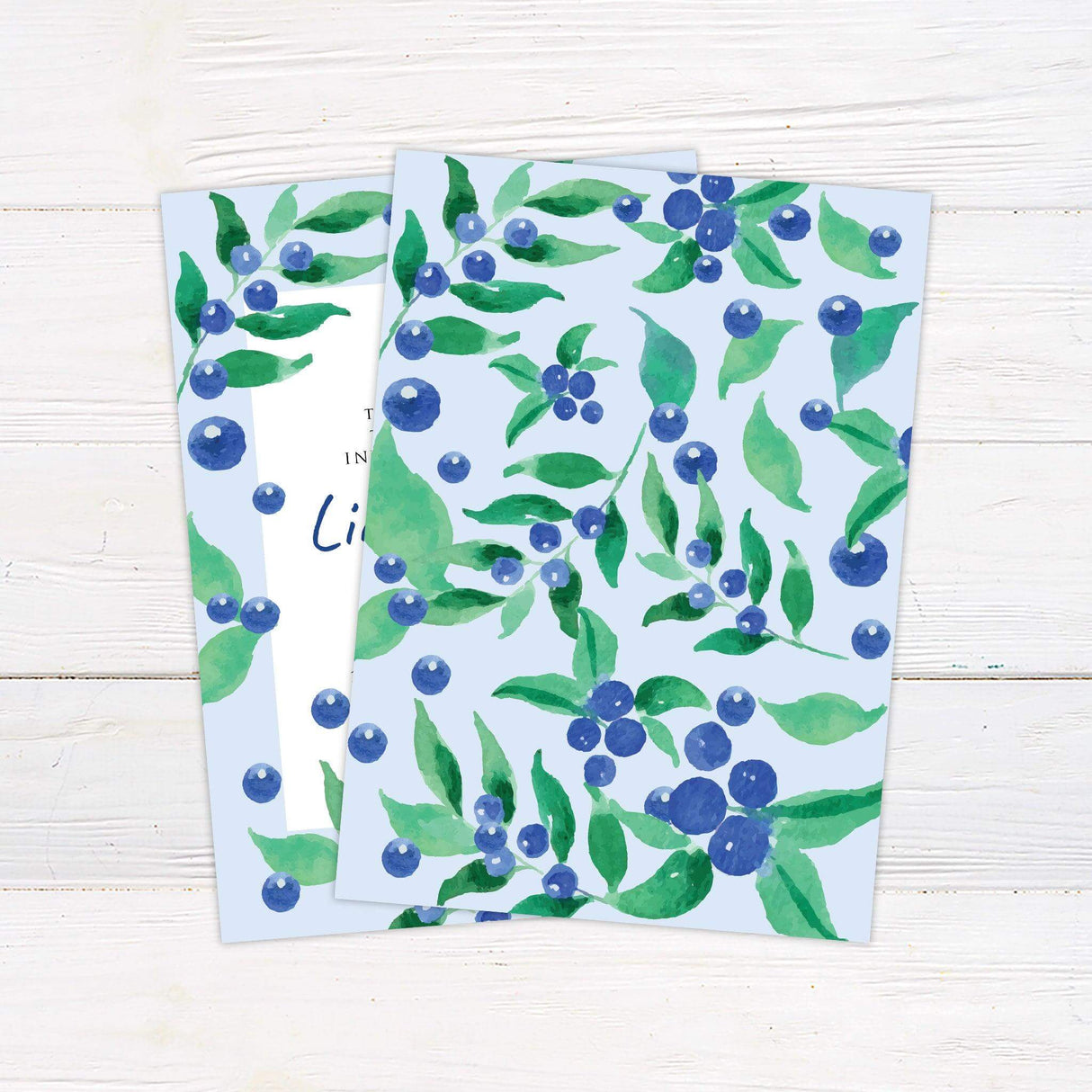 Blueberry-themed wedding invitation with watercolor berries and greenery on a soft blue background, featuring elegant serif and handwritten fonts. back