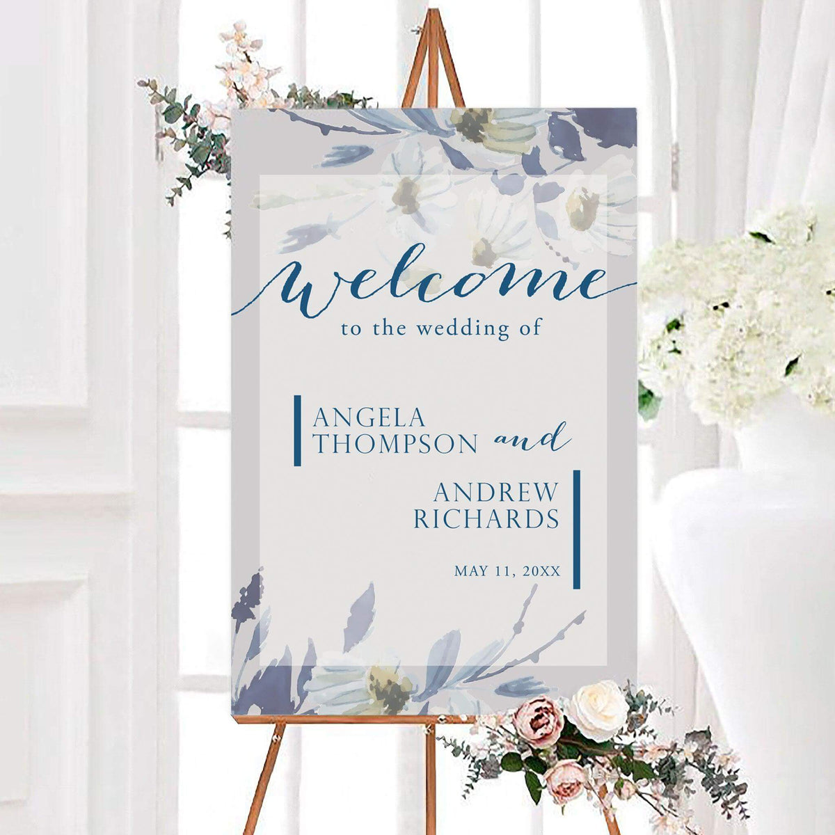 Blue botanical watercolor wedding welcome sign featuring soft flowers, elegant lettering, and personalized names. The design includes the couple’s wedding date with floral artwork framing the top and bottom.