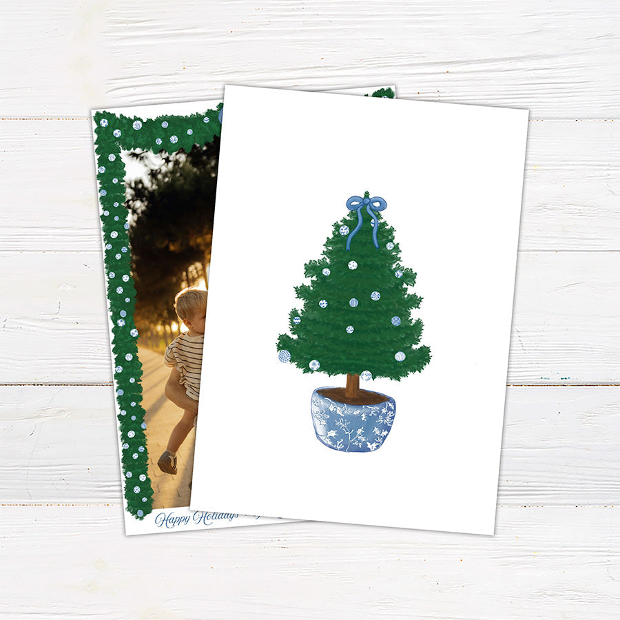A personalized blue Christmas garland family holiday photo card framed with watercolor evergreen garland, blue and white ornaments, and a blue bow. The coordinating design features elegant blue script and a decorated Christmas tree with matching blue accents. - vertical back view.