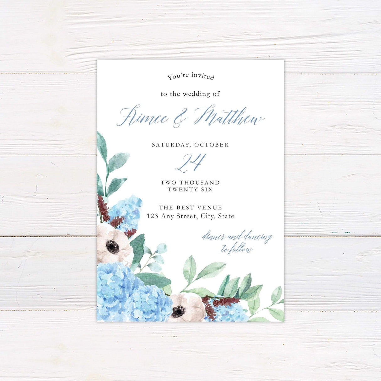 Wedding invitation with watercolor blue hydrangeas, white flowers, and green leaves on a clean white background.