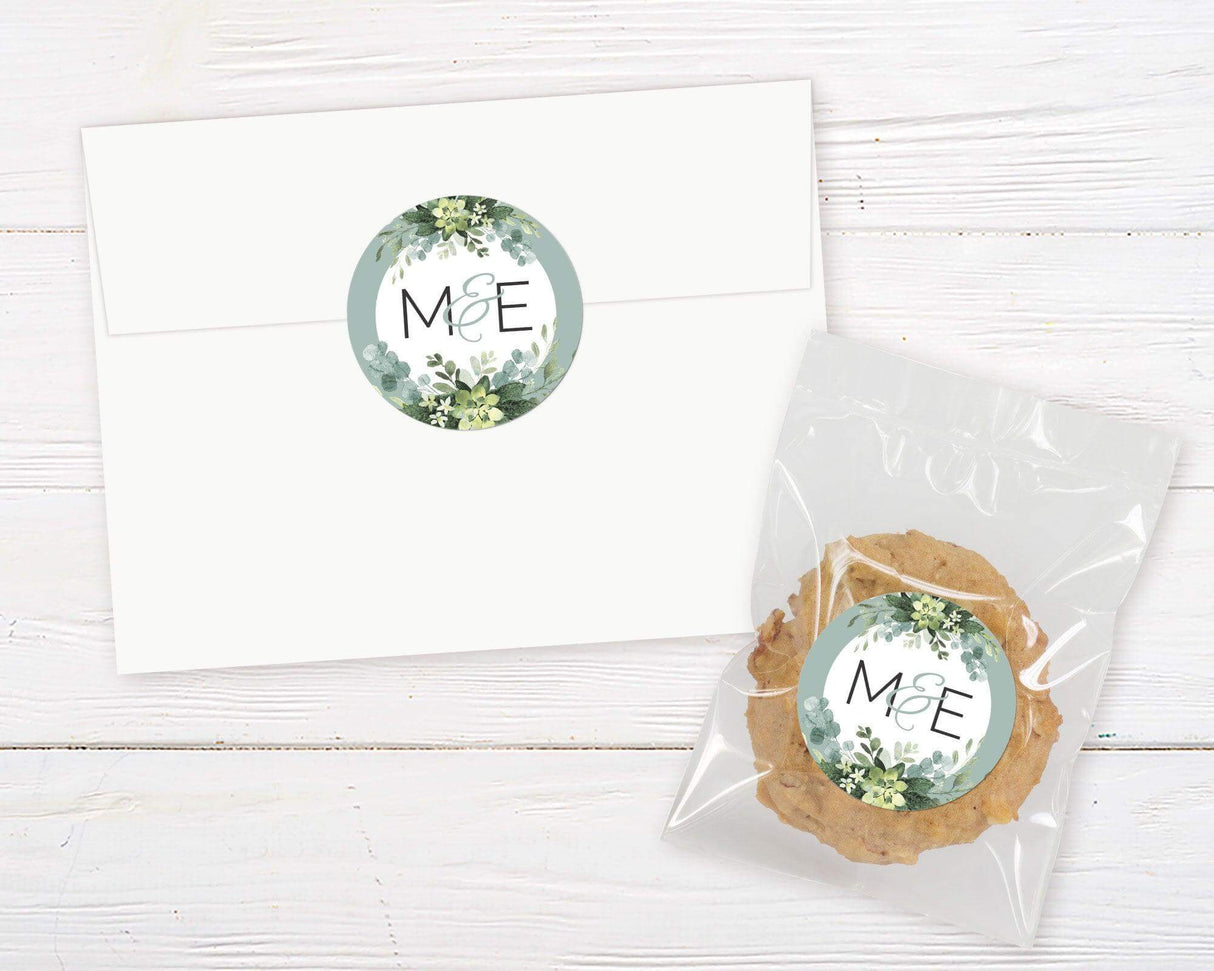 White envelope and cookie package with botanical eucalyptus design label on wooden background.