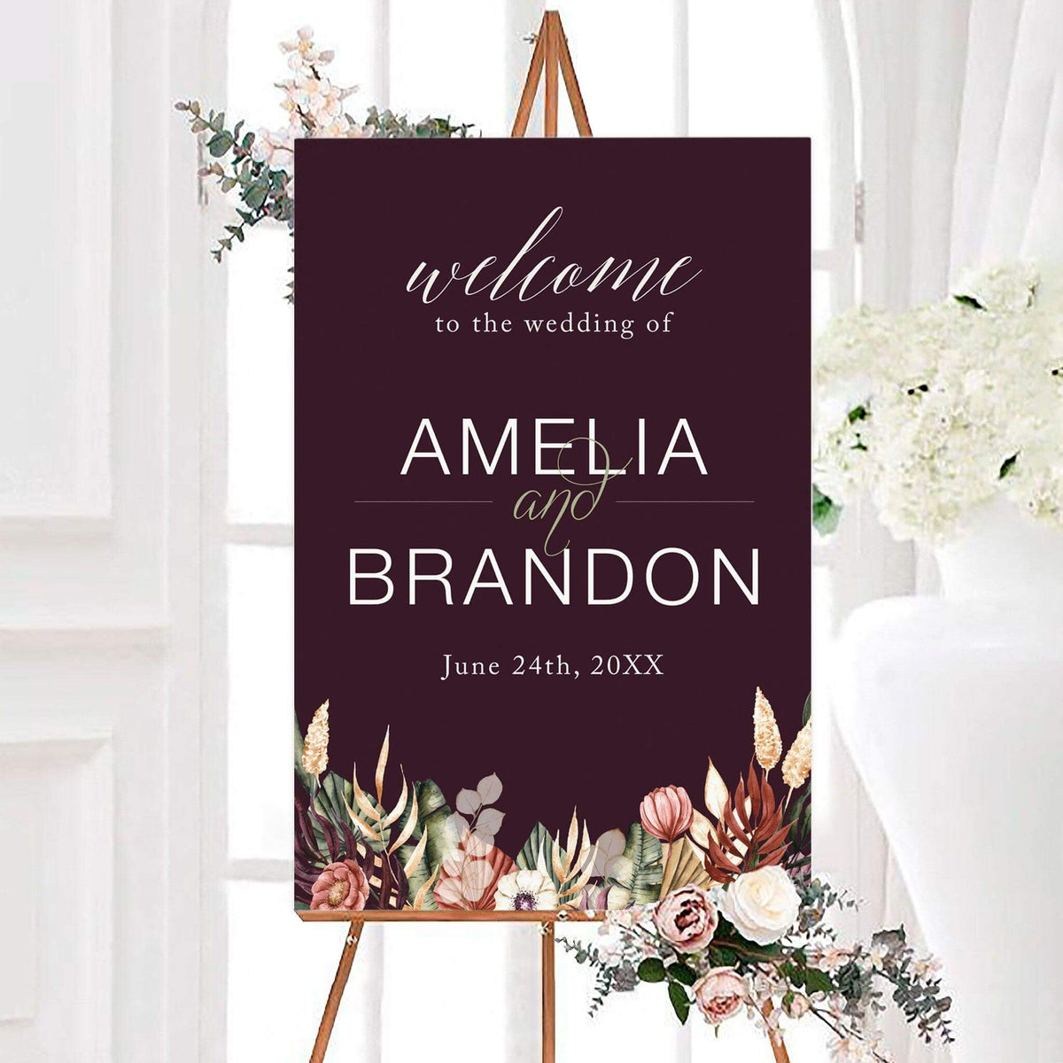 Personalized bohemian floral wedding welcome sign featuring a deep plum background, earthy watercolor flowers, and botanical greenery along the bottom. The elegant floral wedding entrance sign includes customizable couple's names and wedding date in white modern lettering and flowing script.