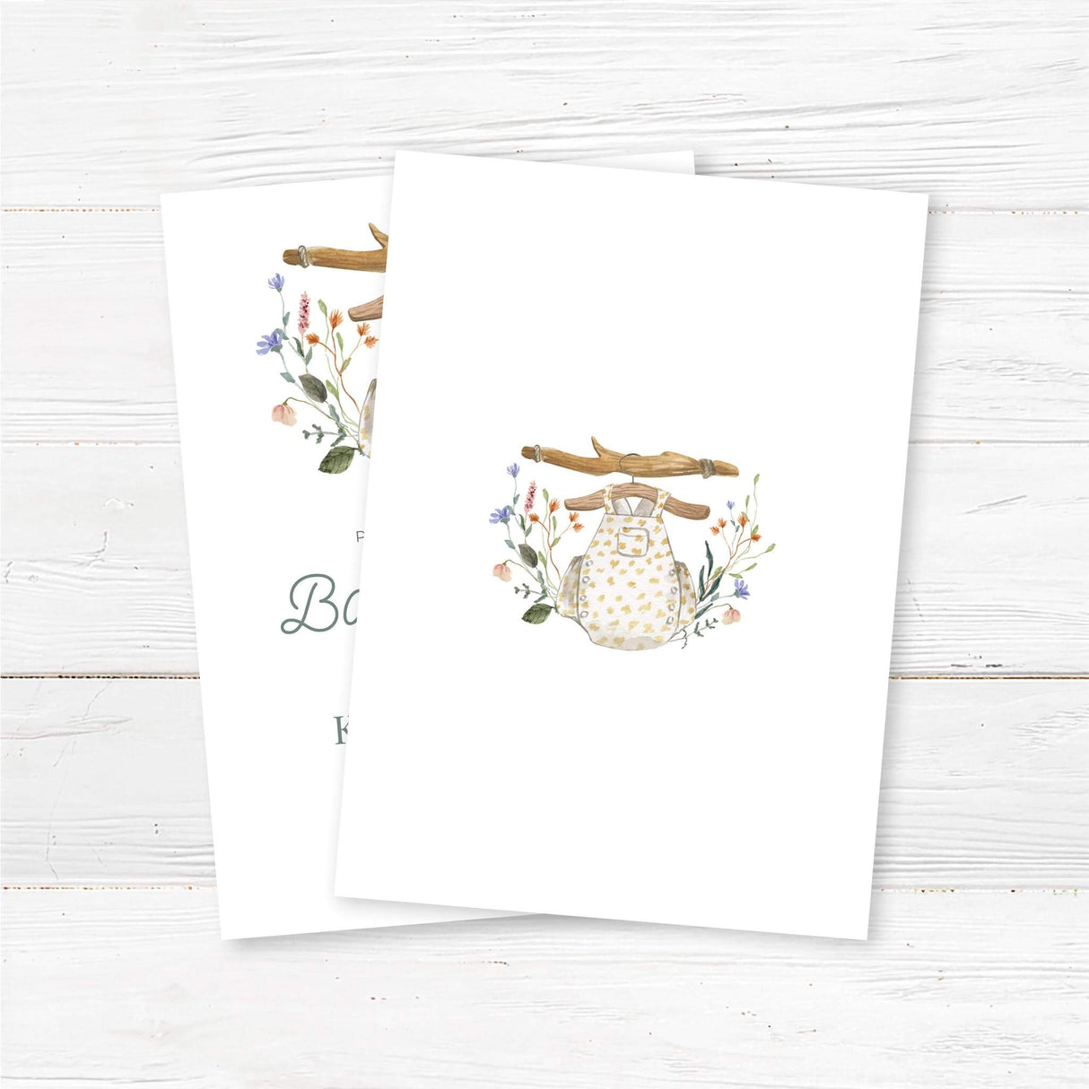 Printed boho baby shower invitation featuring a soft watercolor baby romper on a rustic wooden hanger, surrounded by wildflowers. This elegant and gender-neutral invitation is perfect for a bohemian baby shower, woodland baby sprinkle, or floral country baby shower. Professionally printed on high-quality cardstock with envelopes included. Fully customizable with honoree’s name, date, location, and registry details. back