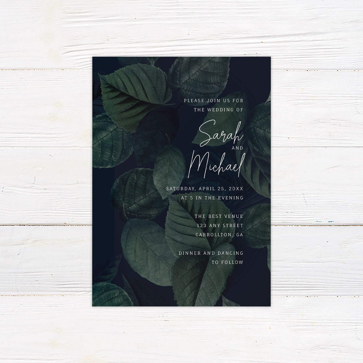 Elegant wedding invitation featuring dark green watercolor leaves with modern script text for a botanical evening wedding