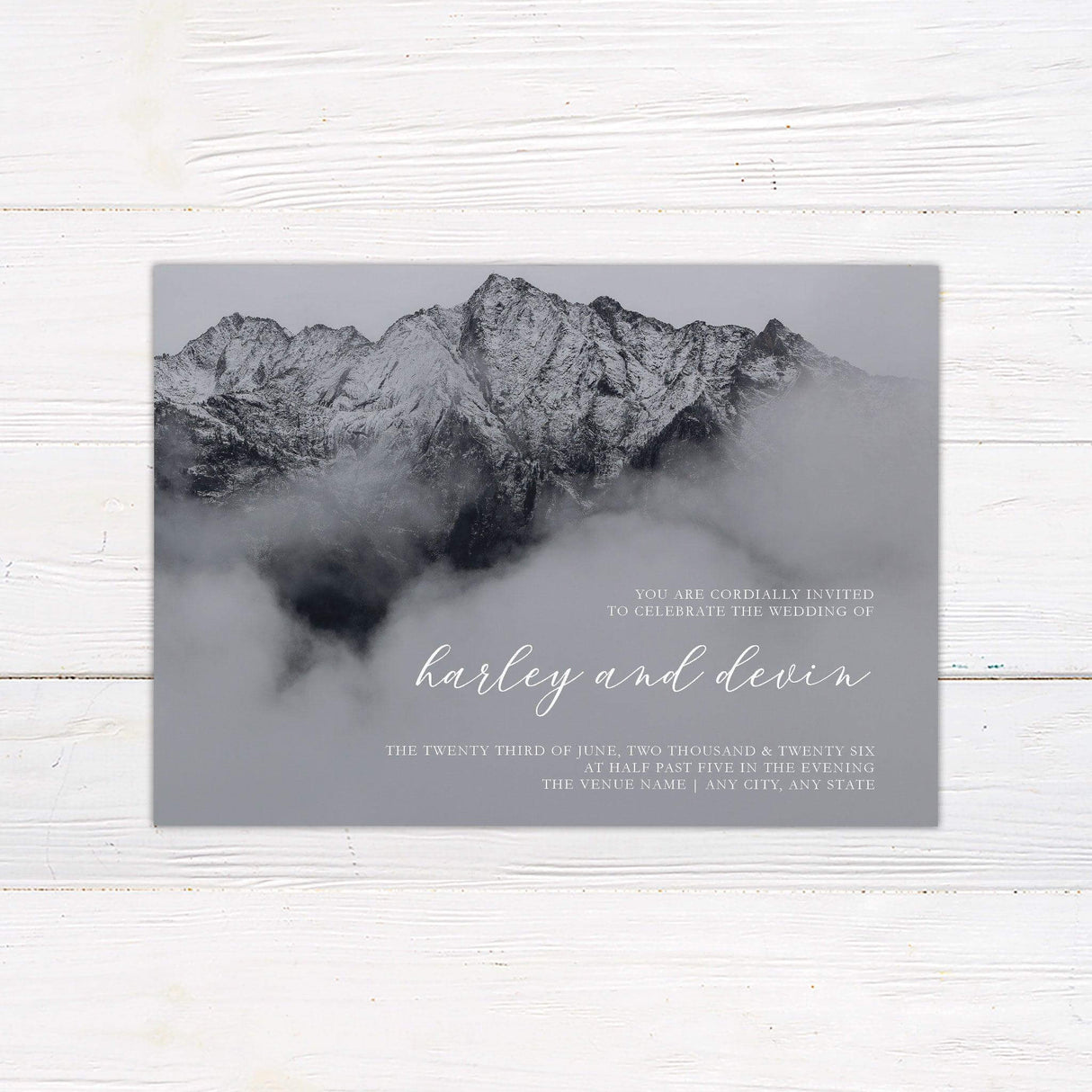Charcoal mountain wedding invitation with snow-covered peaks and fog, featuring elegant white script and serif fonts for a dramatic rustic look.