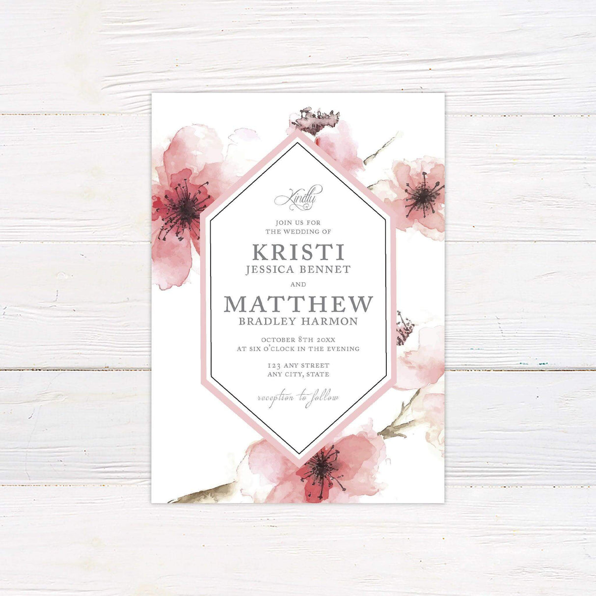 Wedding invitation with blush pink cherry blossom watercolor background and modern geometric frame, featuring serif and script text on a white backdrop.
