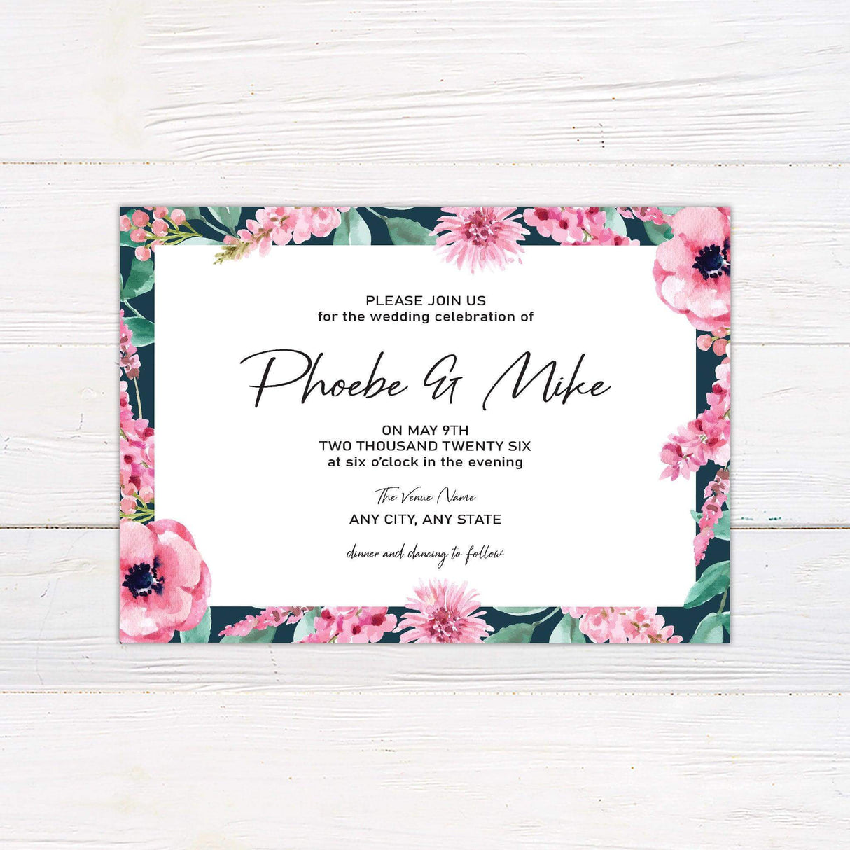 Wedding invitation with bright watercolor pink and purple floral border on navy background and modern script text on a white center panel.