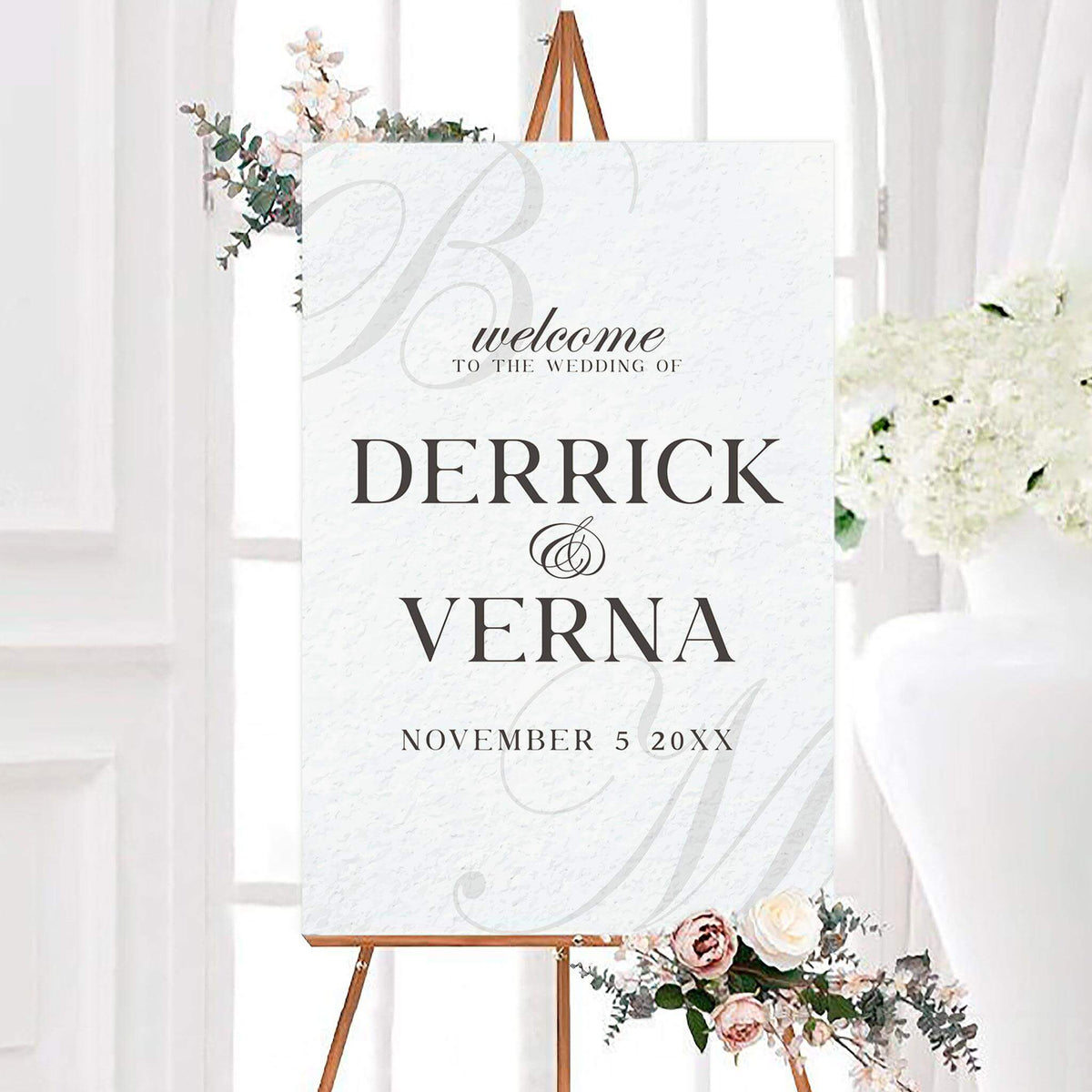 Personalized classic initial wedding welcome sign featuring classic typography and subtle oversized monogram initials in the background. The couple’s names and wedding date are displayed prominently in an elegant layout.
