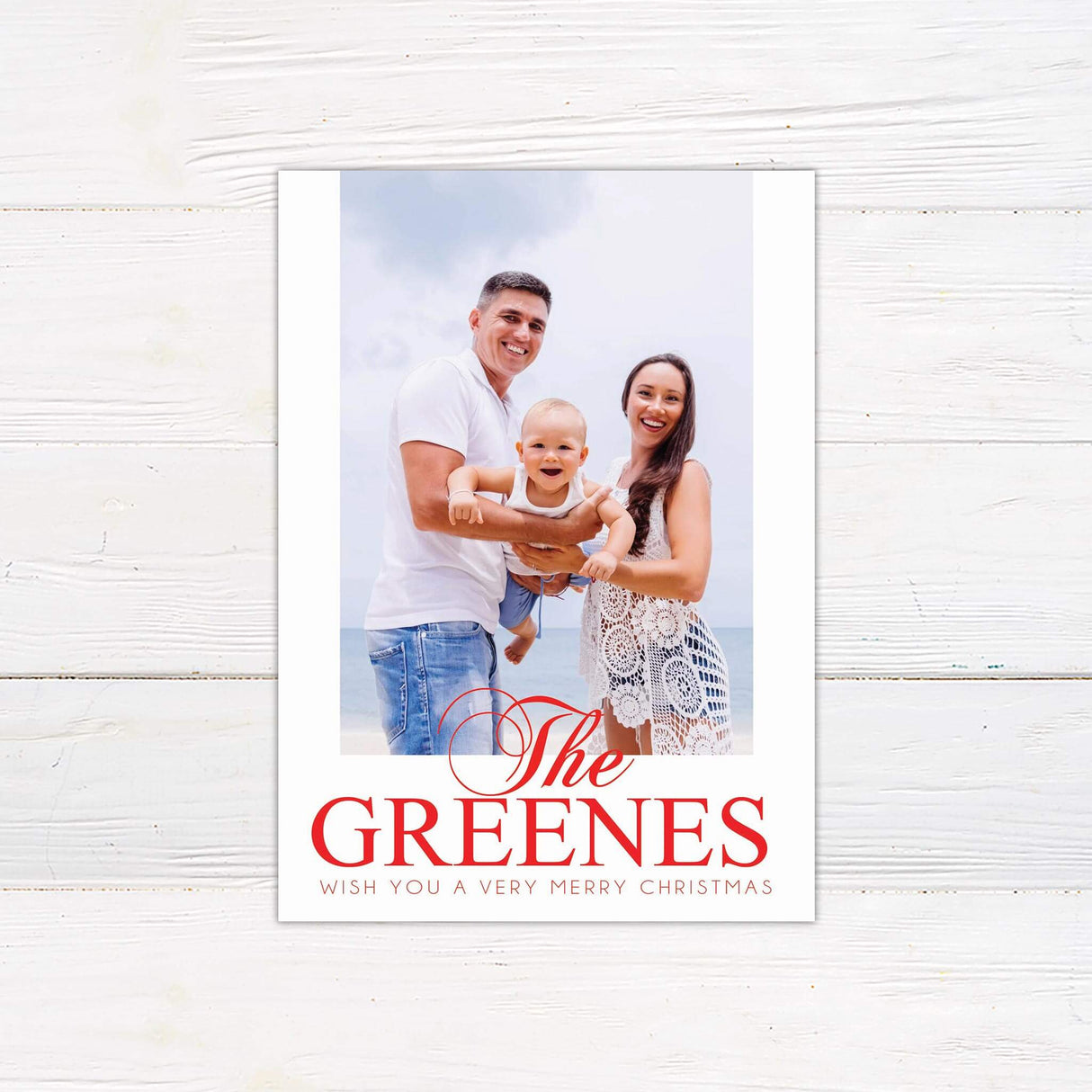 Christmas card with a full customizable photo layout featuring bold red typography of the family name and a festive holiday greeting at the bottom.