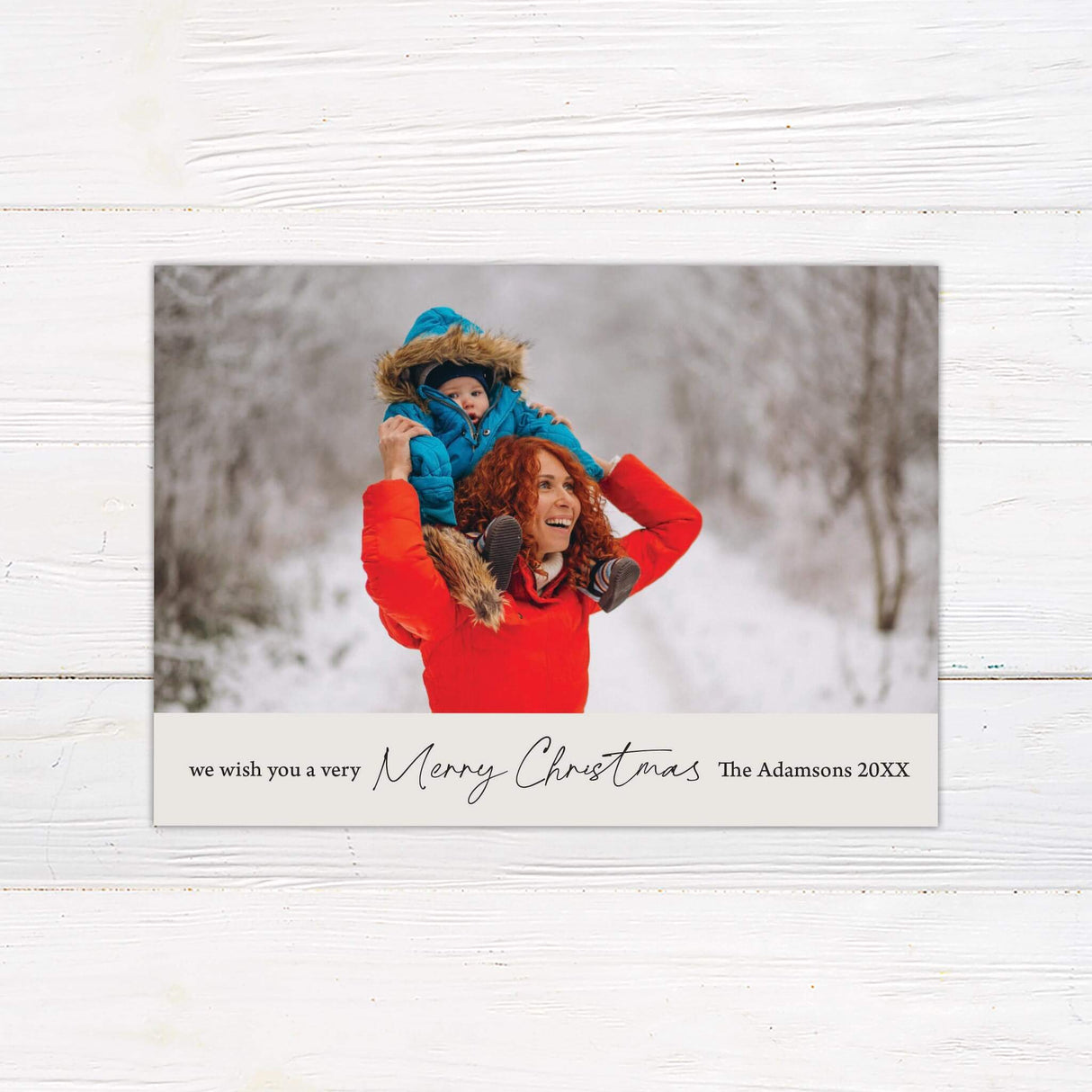 Minimalist holiday card design with a large customizable photo and a simple cream banner featuring Merry Christmas text with family name and year.