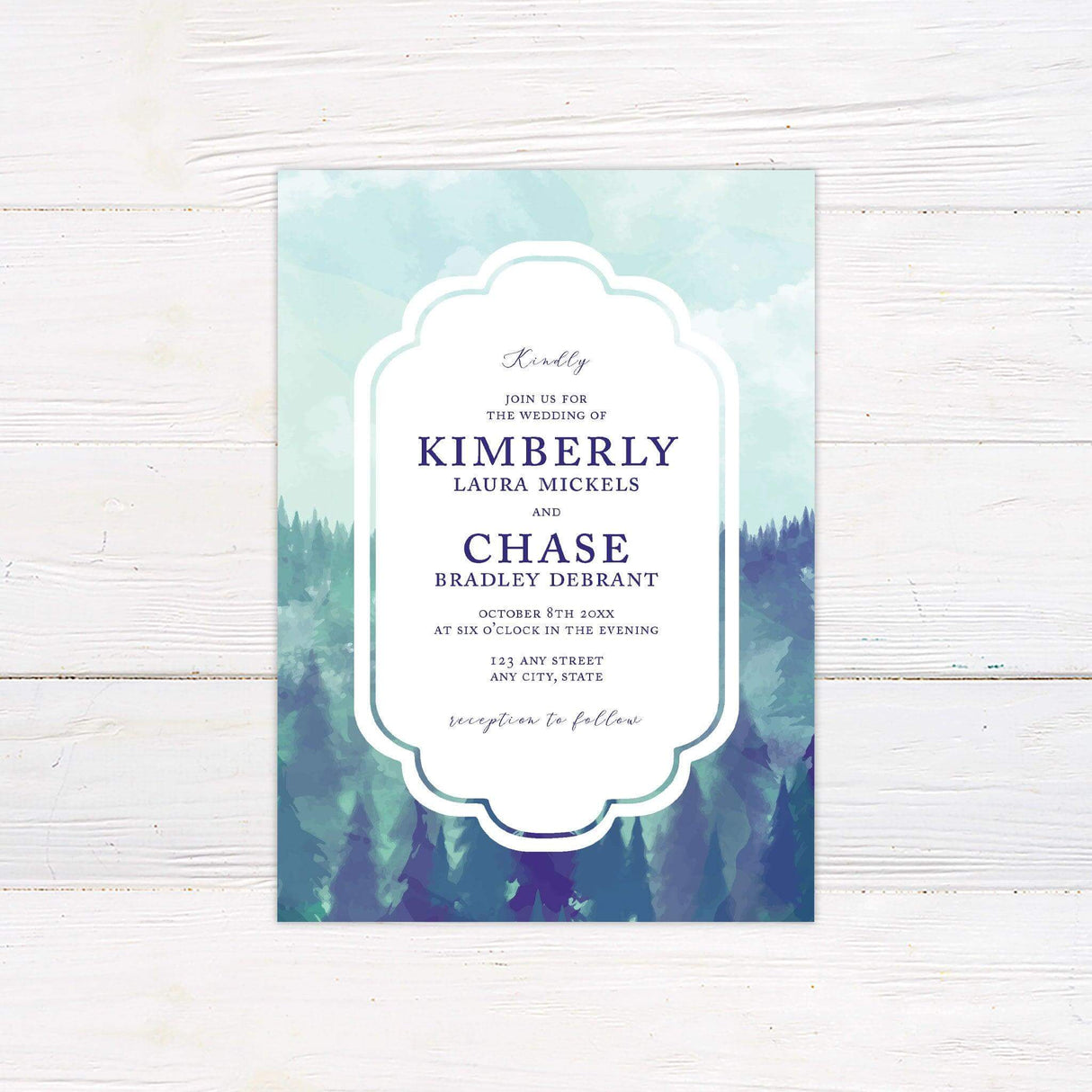 Wedding invitation featuring a misty watercolor mountain and forest background with elegant typography framed in a white ornate border.