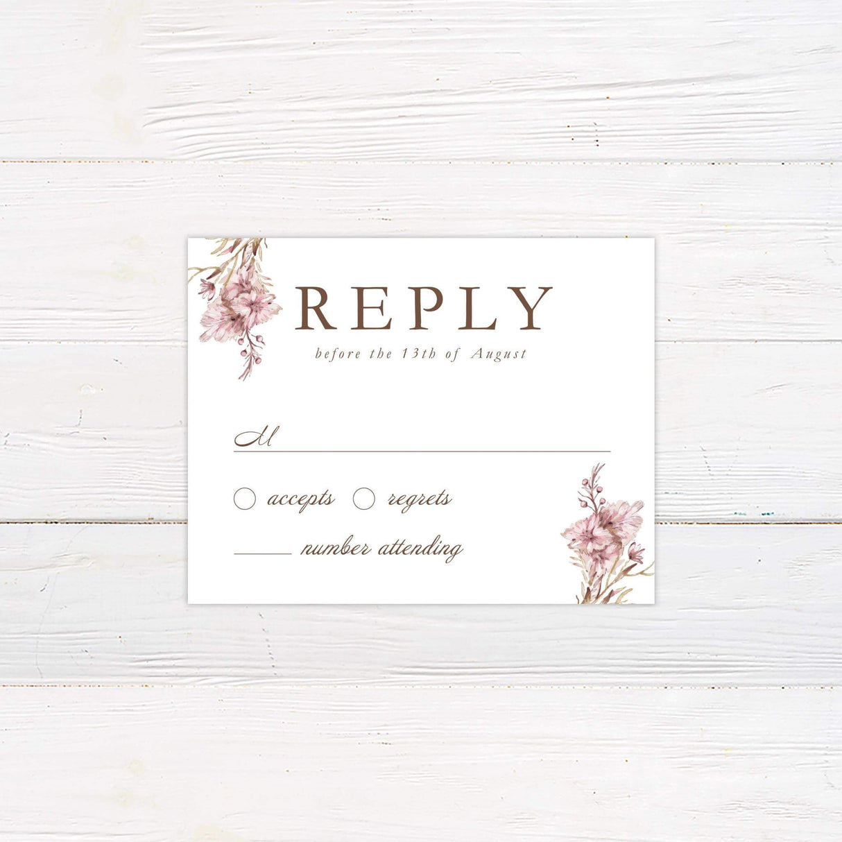 A rsvp card features elegant watercolor floral arrangements in muted pink and brown tones framing the text. The typography is a mix of serif and script fonts, creating a sophisticated and romantic feel. Event details, including the date, time, and venue, are clearly displayed in a balanced layout. This design exudes timeless elegance, making it perfect for vintage, boho, or garden-inspired wedding celebrations.