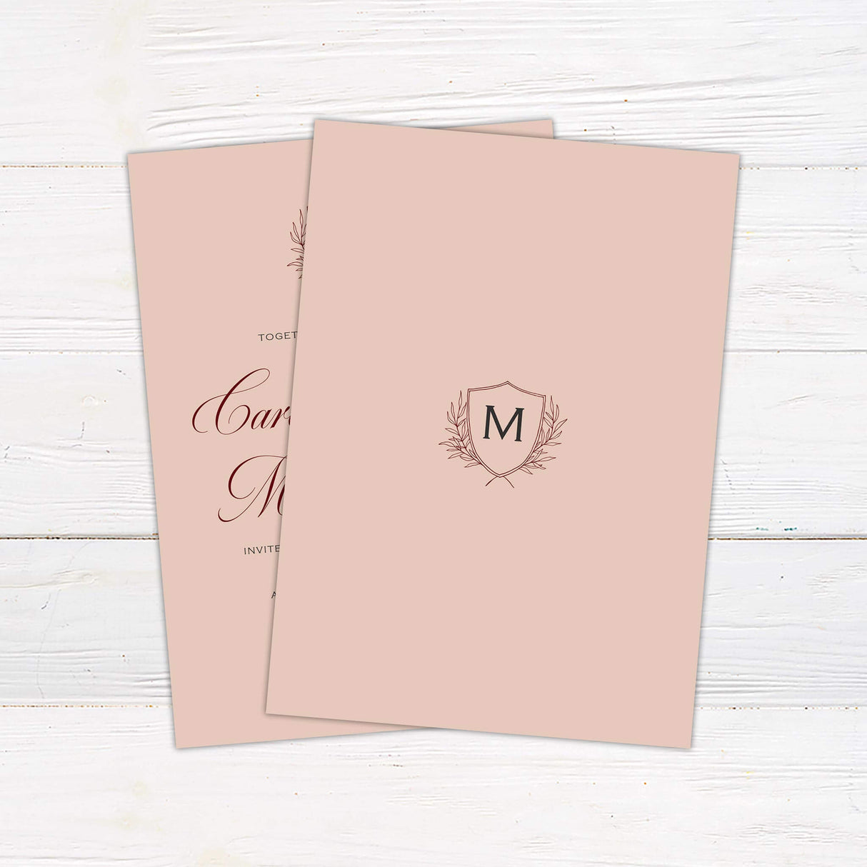 A wedding invitation with a blush background features an elegant monogram crest at the top, accented by delicate laurel details. The text is arranged in a mix of flowing script and classic serif fonts, creating a timeless and sophisticated look. Event details, including the date, time, and venue, are displayed in a structured and refined layout. This design exudes elegance and charm, perfect for a formal, classic, or vintage-inspired wedding celebration. Back
