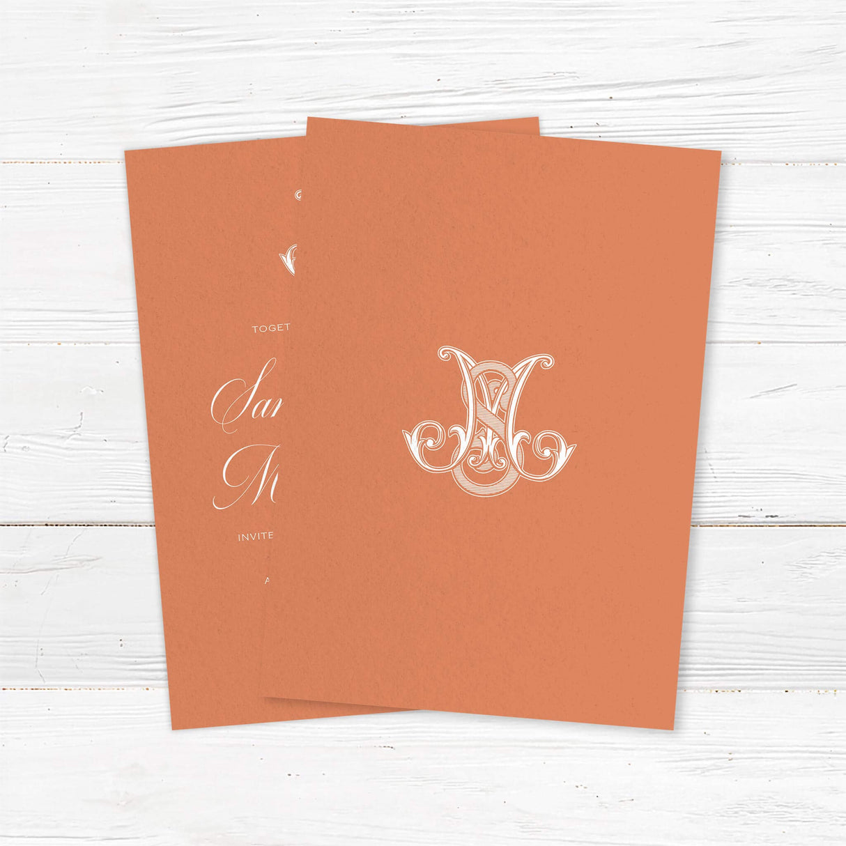 Terracotta wedding invitation with white calligraphy and ornate Celtic-style monogram - back side