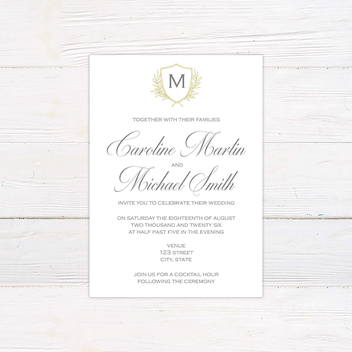 Wedding invitation with delicate monogram crest, gold shield and laurel, script and serif fonts on a soft ivory background