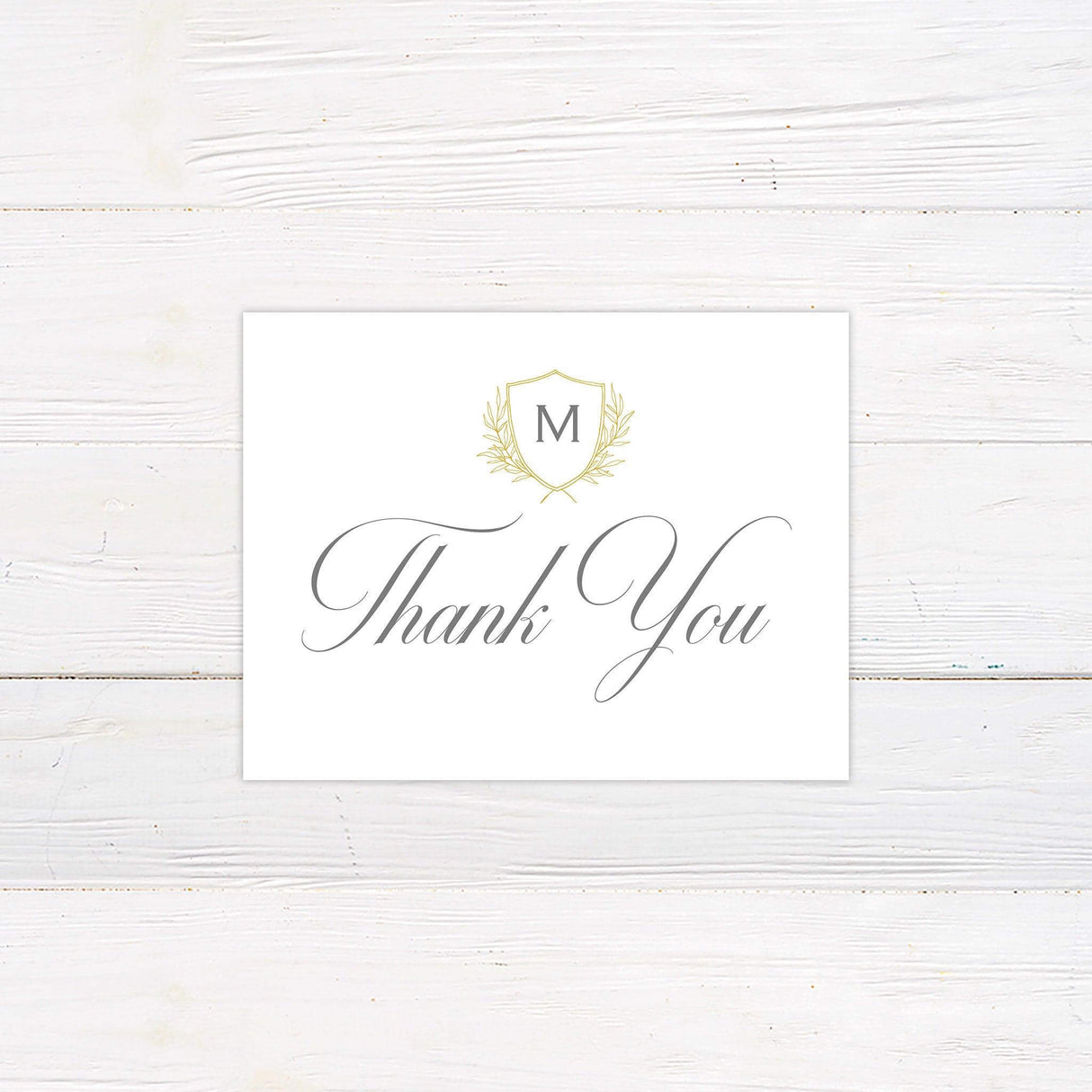 Elegant thank you card with monogram crest and laurel design in gold on ivory background, featuring classic calligraphy script.