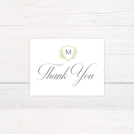 Elegant thank you card with monogram crest and laurel design in gold on ivory background, featuring classic calligraphy script.