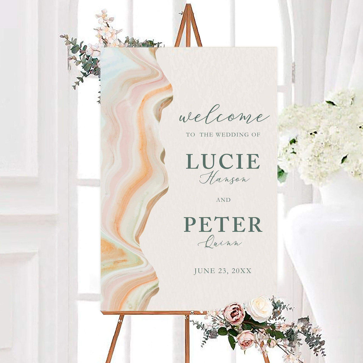 Modern desert sand wedding welcome sign with a flowing watercolor agate-inspired border and softly textured background. The personalized design features the couple’s names and wedding date in elegant script and serif lettering.