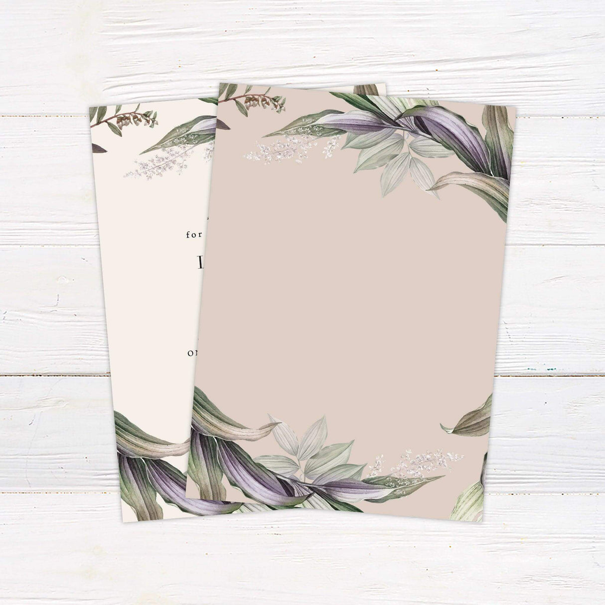 Elegant wedding invitation with watercolor botanical foliage in green and violet shades, featuring serif and script text on a cream background. - back