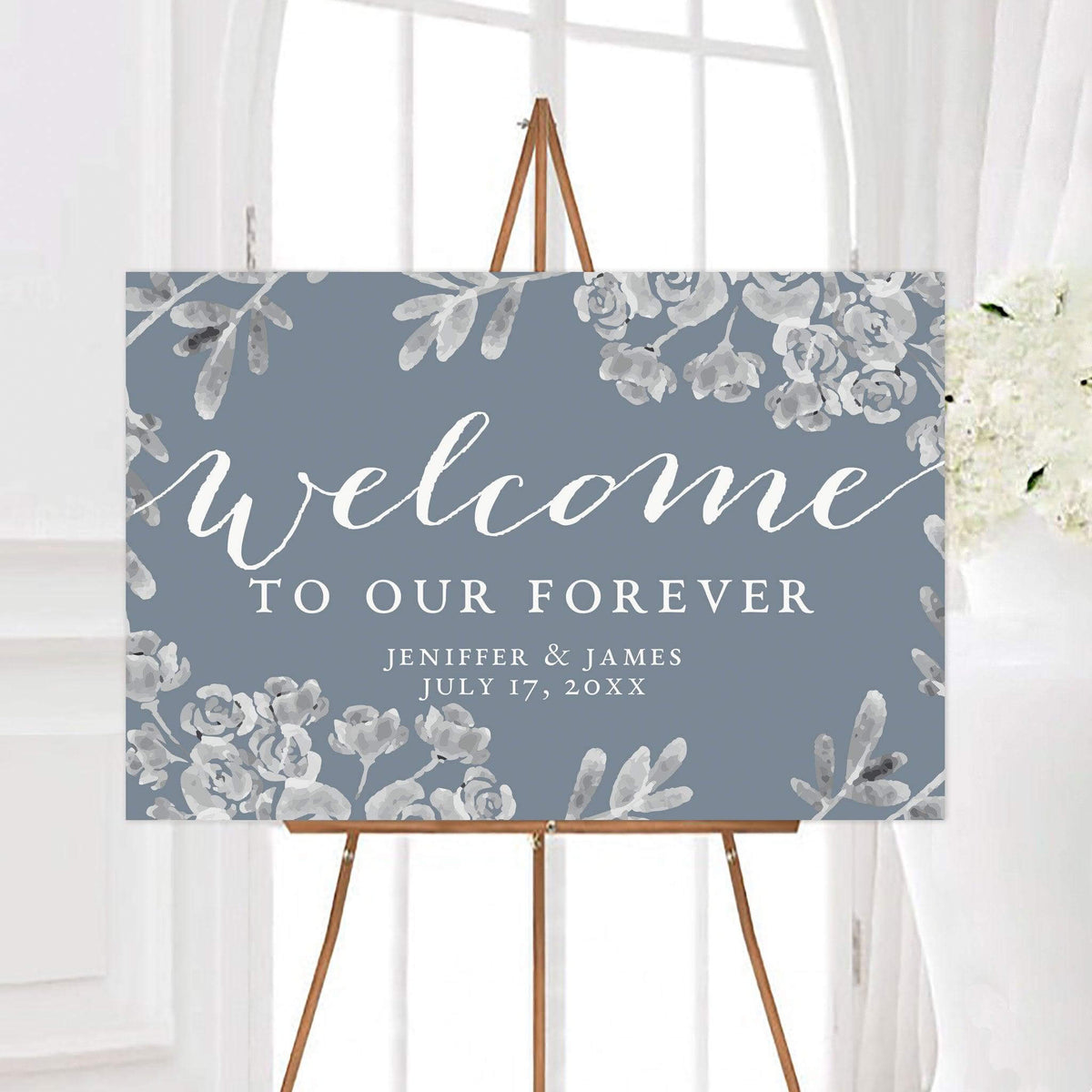 Dusty blue gray floral wedding welcome sign featuring the phrase “Welcome to Our Forever” surrounded by elegant botanical flowers. The sign is personalized with the couple’s names and wedding date.