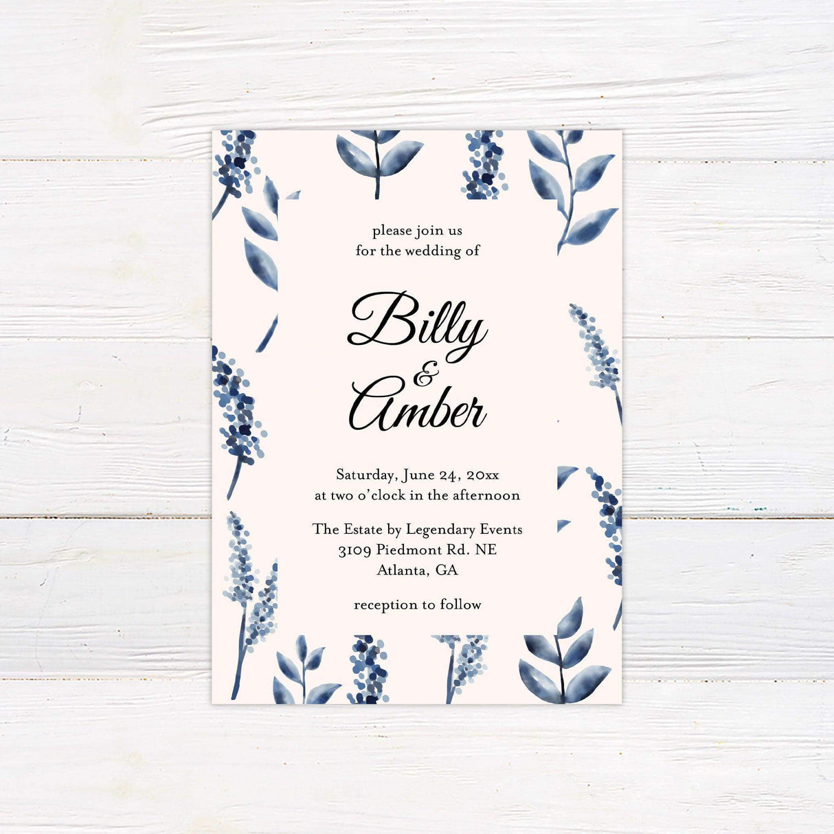 Elegant wedding invitation with blue watercolor leaves and berries framing black script text on a cream background