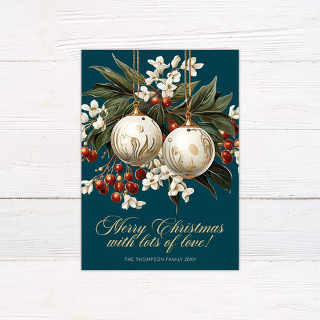 Elegant gold ornament Christmas card with gold ornaments, white winter florals, red berries, and greenery on a dark green background with gold script text