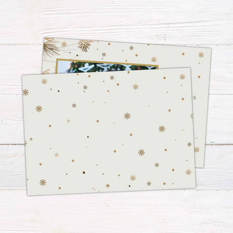 Custom holiday card with a gold frame for a photo, cream background decorated with pine branches and snowflakes, and Merry Christmas text with family name. - back
