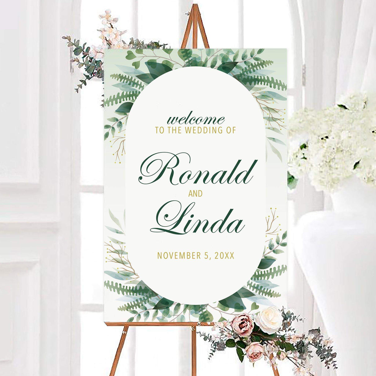 Elegant green botanical arch wedding welcome sign featuring a white arched center surrounded by lush green botanical leaves and delicate branches. Personalized script displays the couple’s names with coordinating wedding details and date.
