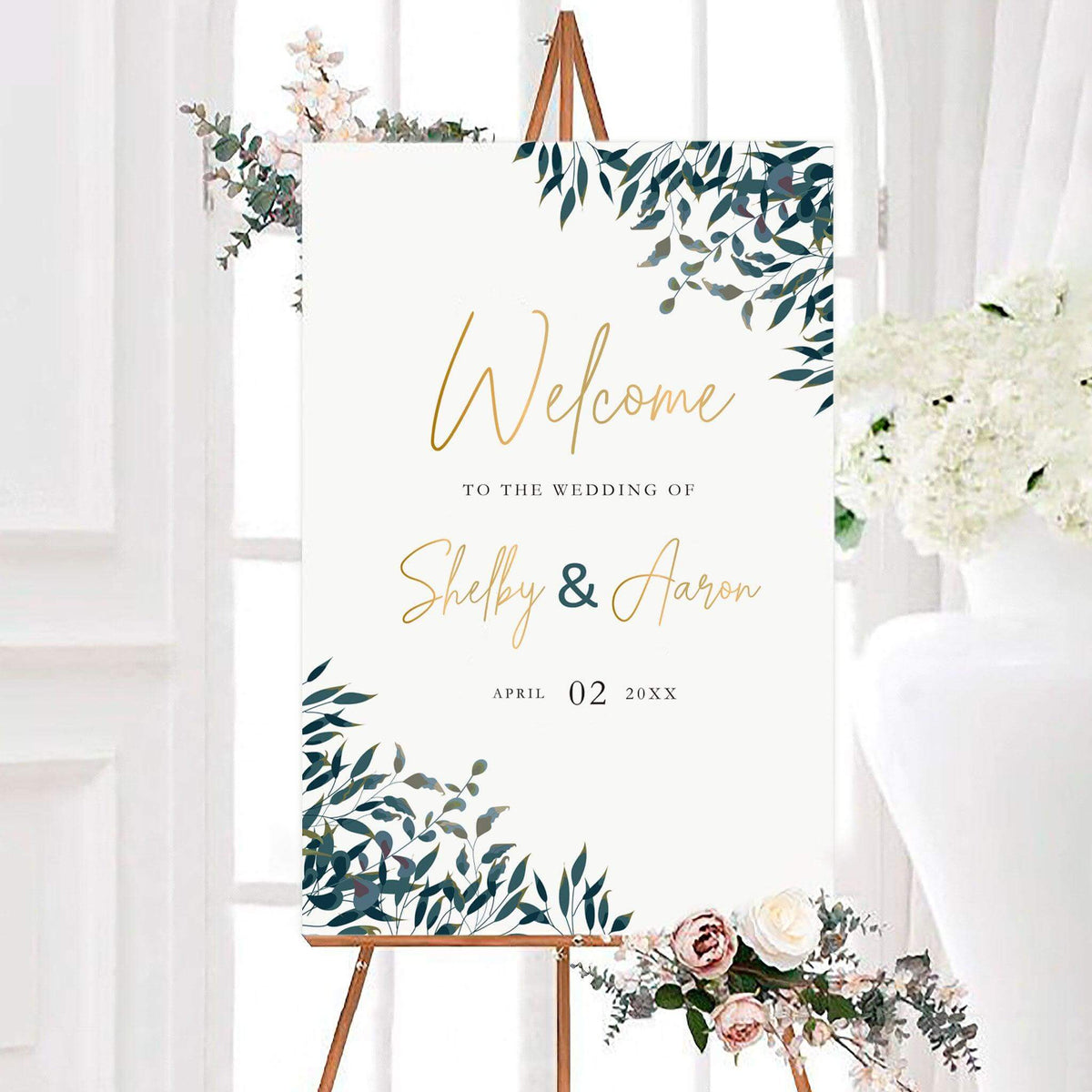 Elegant green leaves wedding welcome sign featuring leafy greenery, elegant script lettering, and personalized names. The sign includes the couple’s wedding date with greenery framing opposite corners.