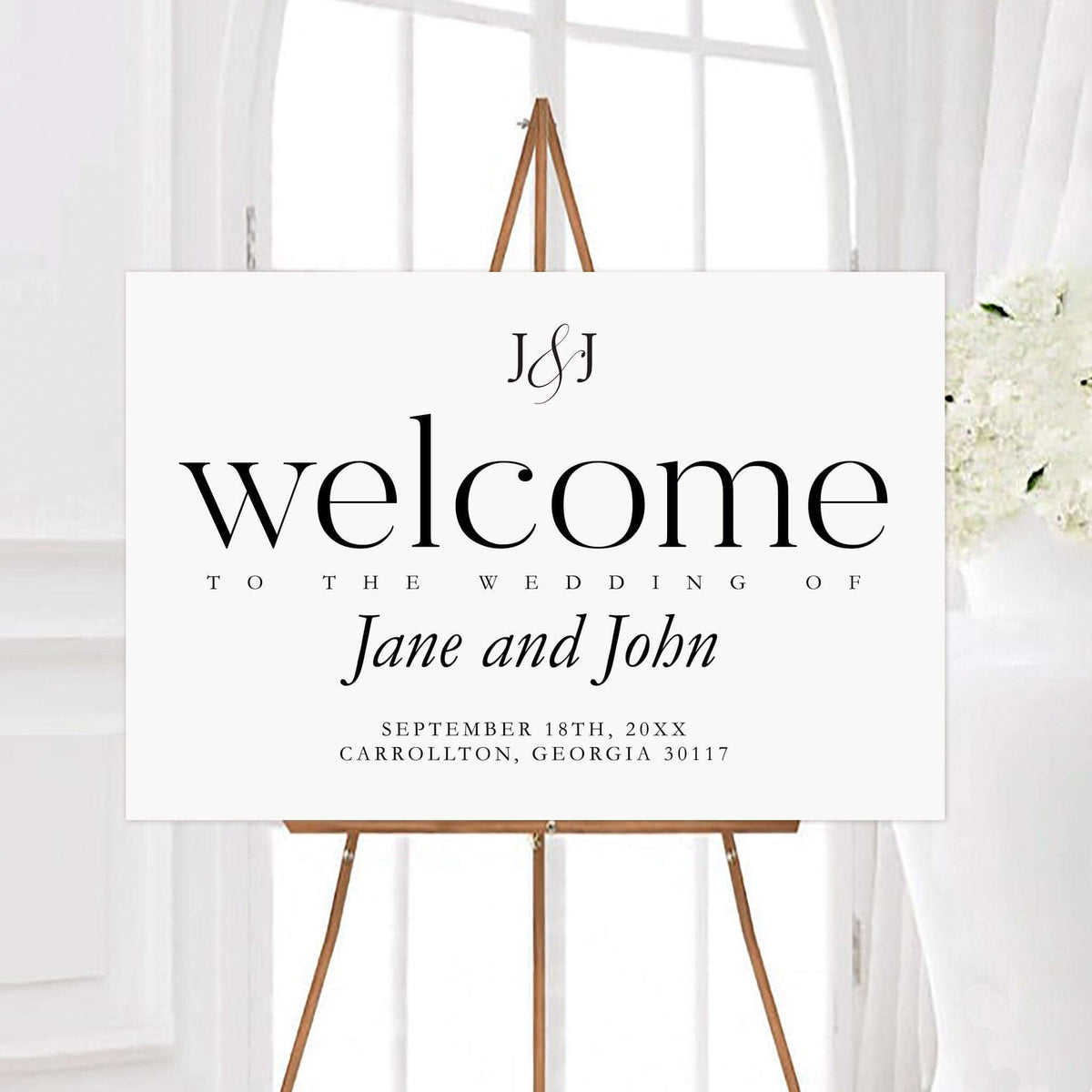 Elegant lines wedding welcome sign displayed on a wooden easel with a custom couple monogram. The clean design features the couple’s names, wedding date, and location in classic black typography.
