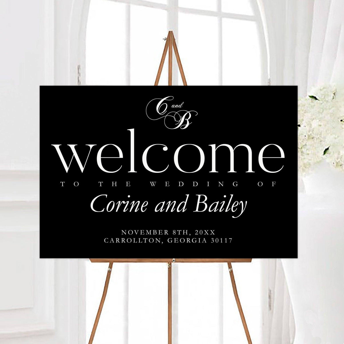 Elegant formal black and white wedding welcome sign featuring a personalized intertwined monogram and large classic typography. The design includes the couple’s names, wedding date, and location in crisp white lettering.