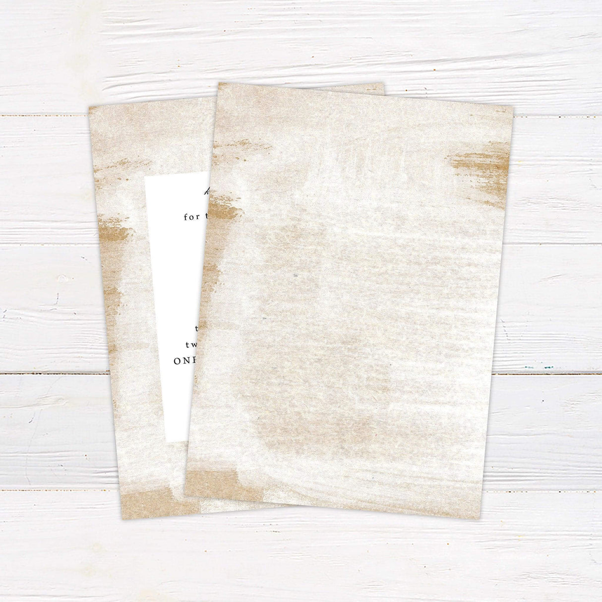 Minimalist wedding invitation with white center panel, soft beige and gold sand-textured background, and elegant serif fonts on a neutral-toned design. back