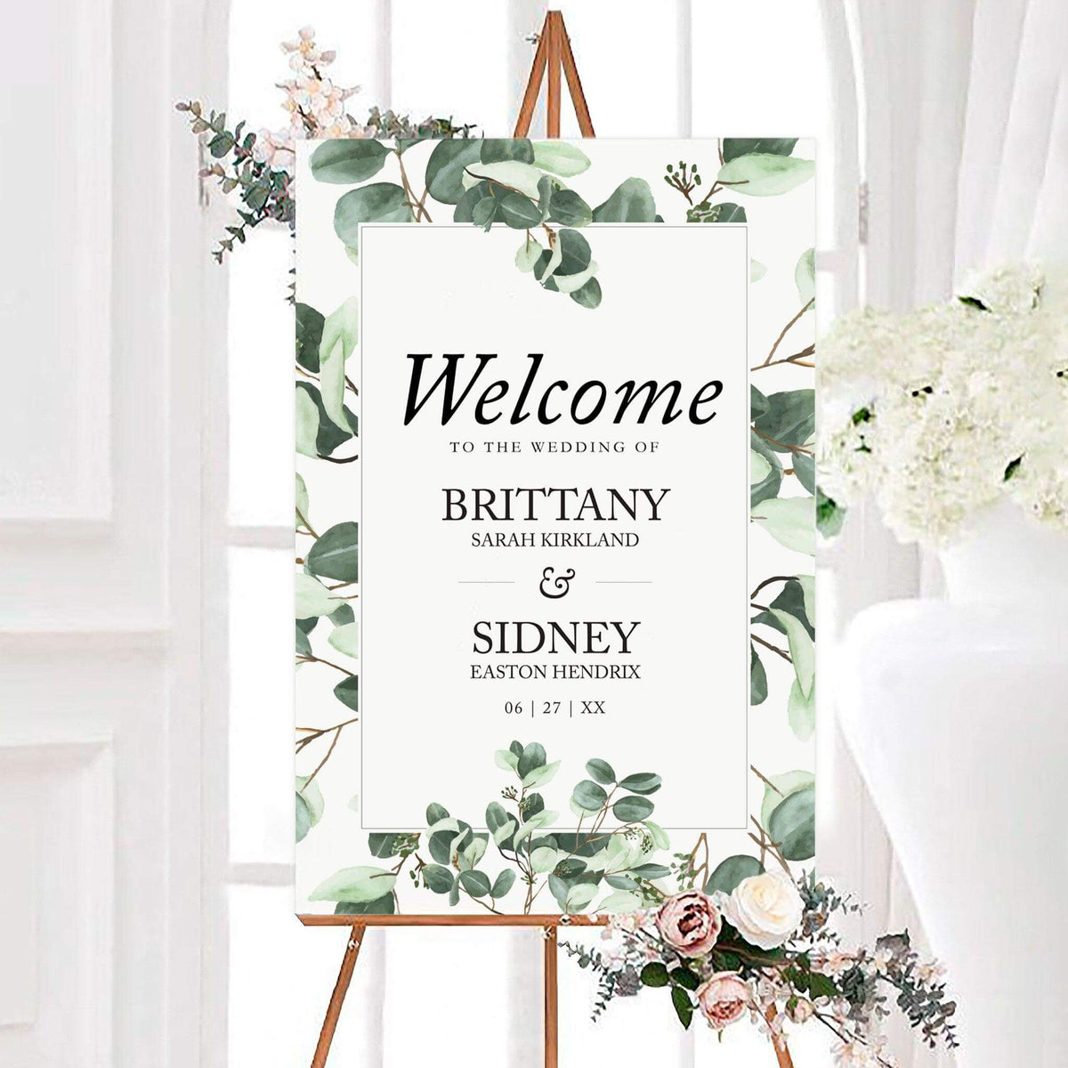Personalized eucalyptus branch wedding welcome sign framed with watercolor eucalyptus branches and soft greenery. The center displays the couple’s names and wedding date in elegant typography.