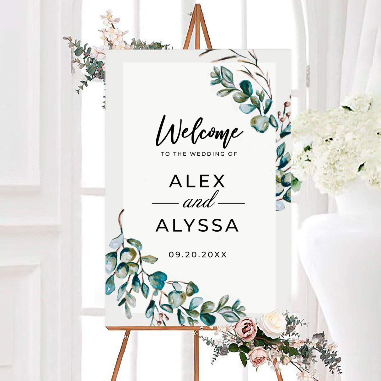 Eucalyptus wreath wedding welcome sign featuring watercolor eucalyptus branches in soft green, teal, and olive tones with modern black lettering. The sign is personalized with the couple’s names and wedding date.