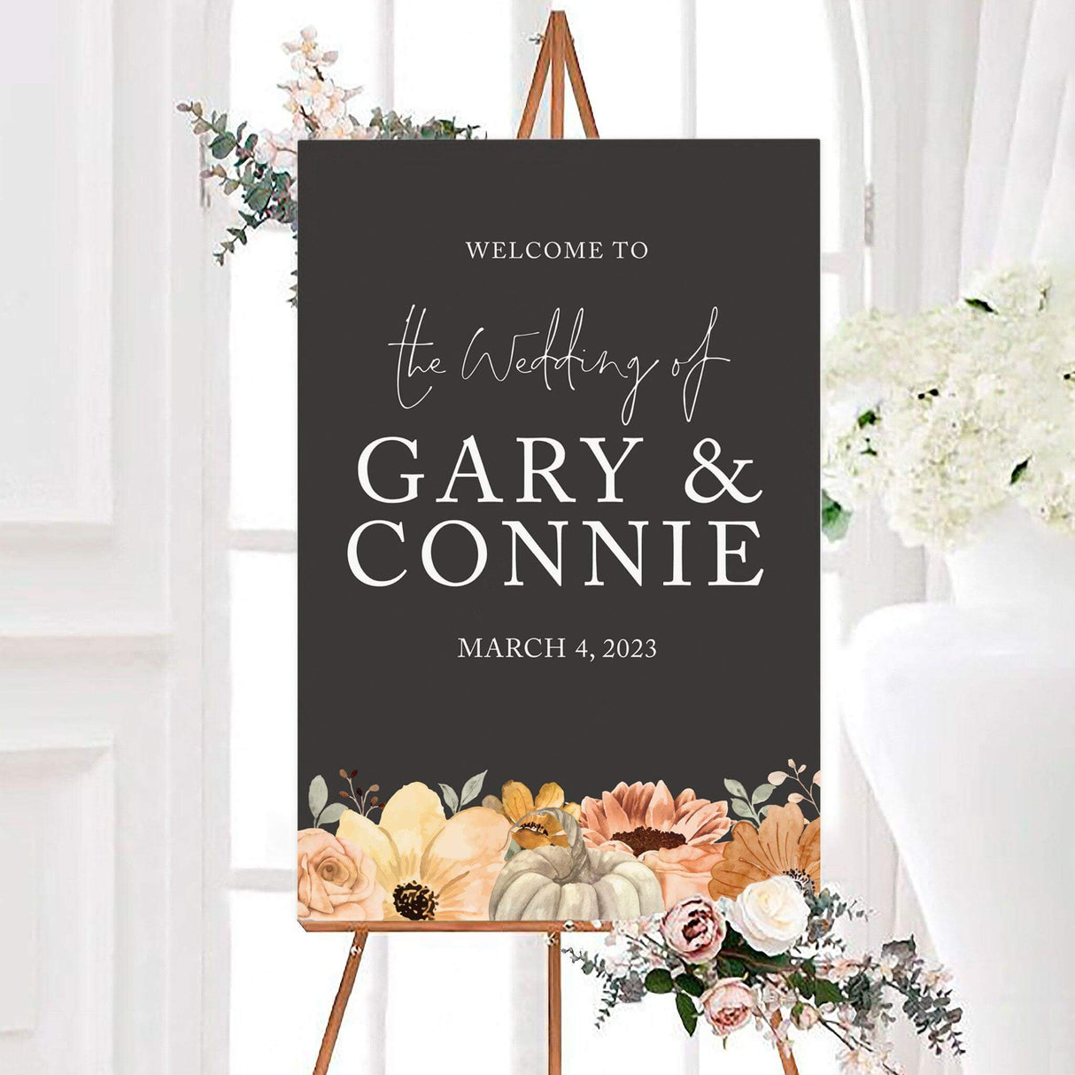 Fall floral wedding welcome sign featuring watercolor flowers, greenery, and a pumpkin along the bottom of a dark background. The personalized design includes the couple’s names and wedding date in elegant white lettering.